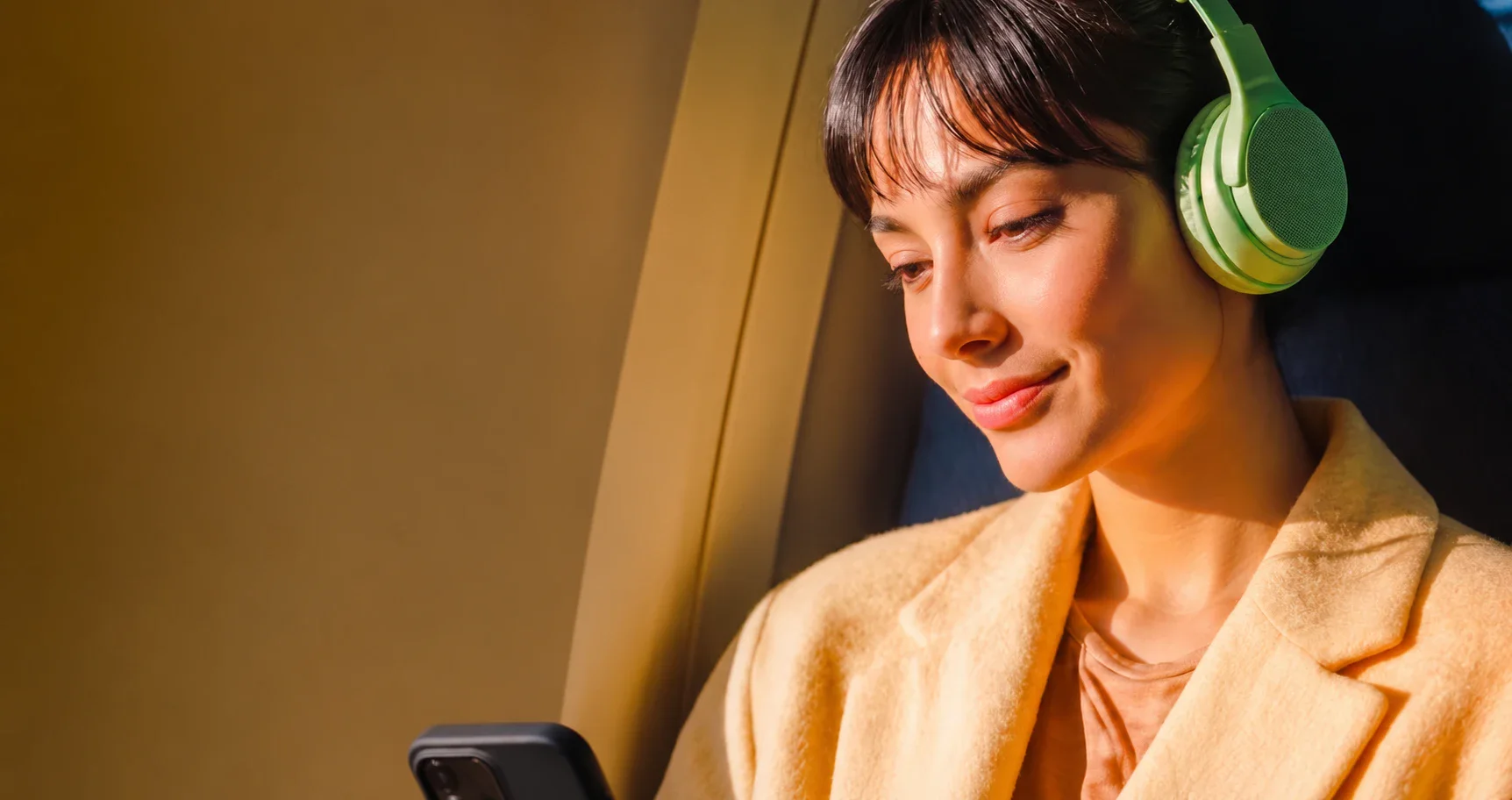 Employee with headphones on a train, looking at her phone